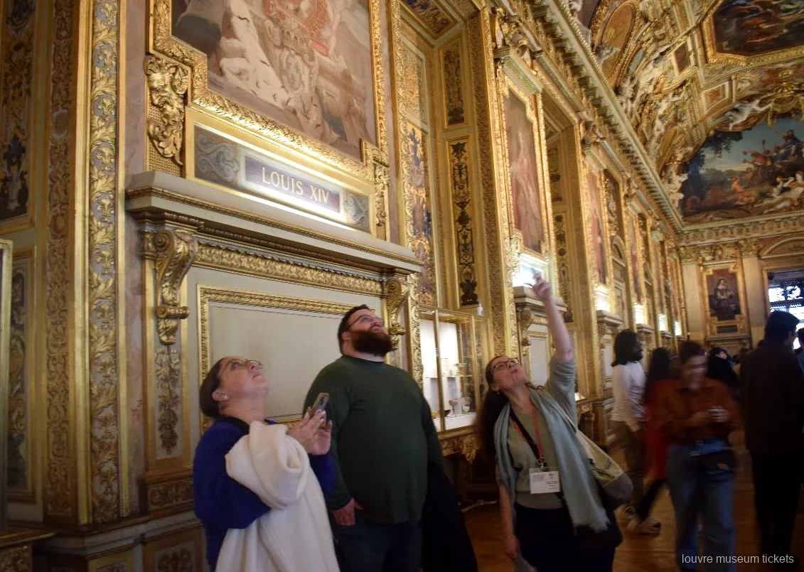 Kleine Gruppe blickt zur bemalten, vergoldeten Decke der Apollon Galerie hinauf, Führung mit Louvre Tickets