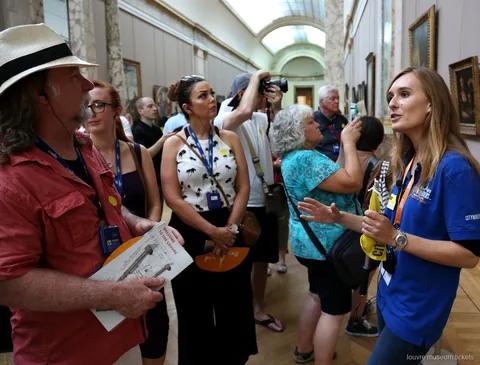 Resim galerisinde Louvre haritaları tutan gruba anlatım yapan rehber, Louvre Müzesi biletleri ile rehberli tur