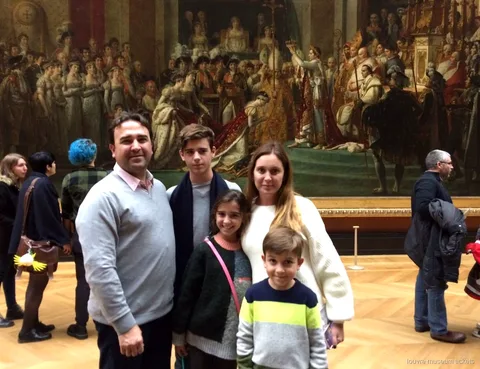 Family of five posing before the Coronation of Napoleon on a private tour with Louvre Museum tickets