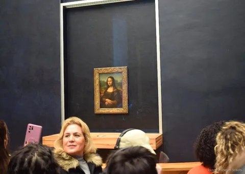 Visitantes diante da Mona Lisa atrás do vidro na parede escura, ponto alto da visita com bilhetes Museu do Louvre